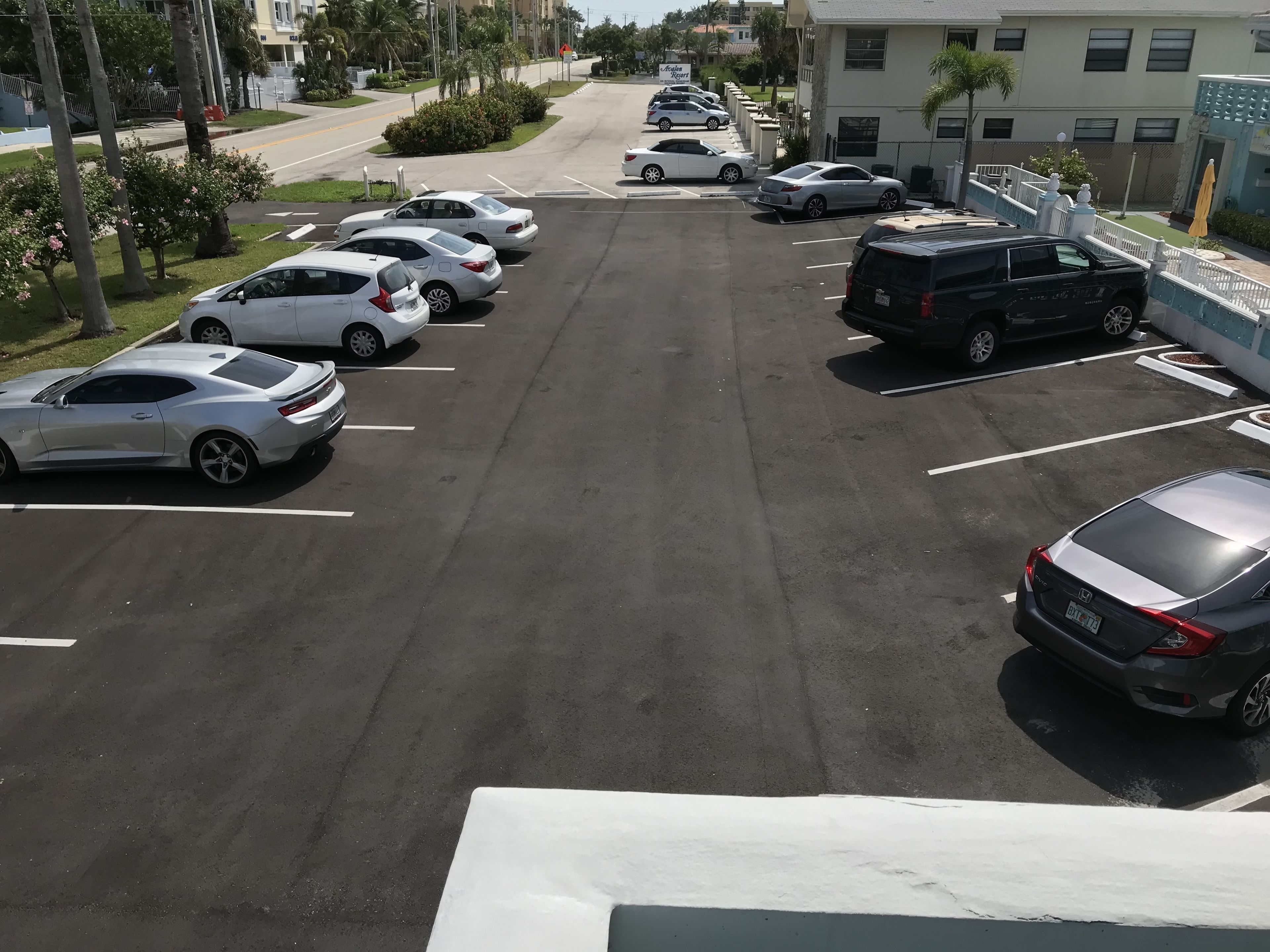 A parking lot with several cars, including a black SUV and a white sedan.