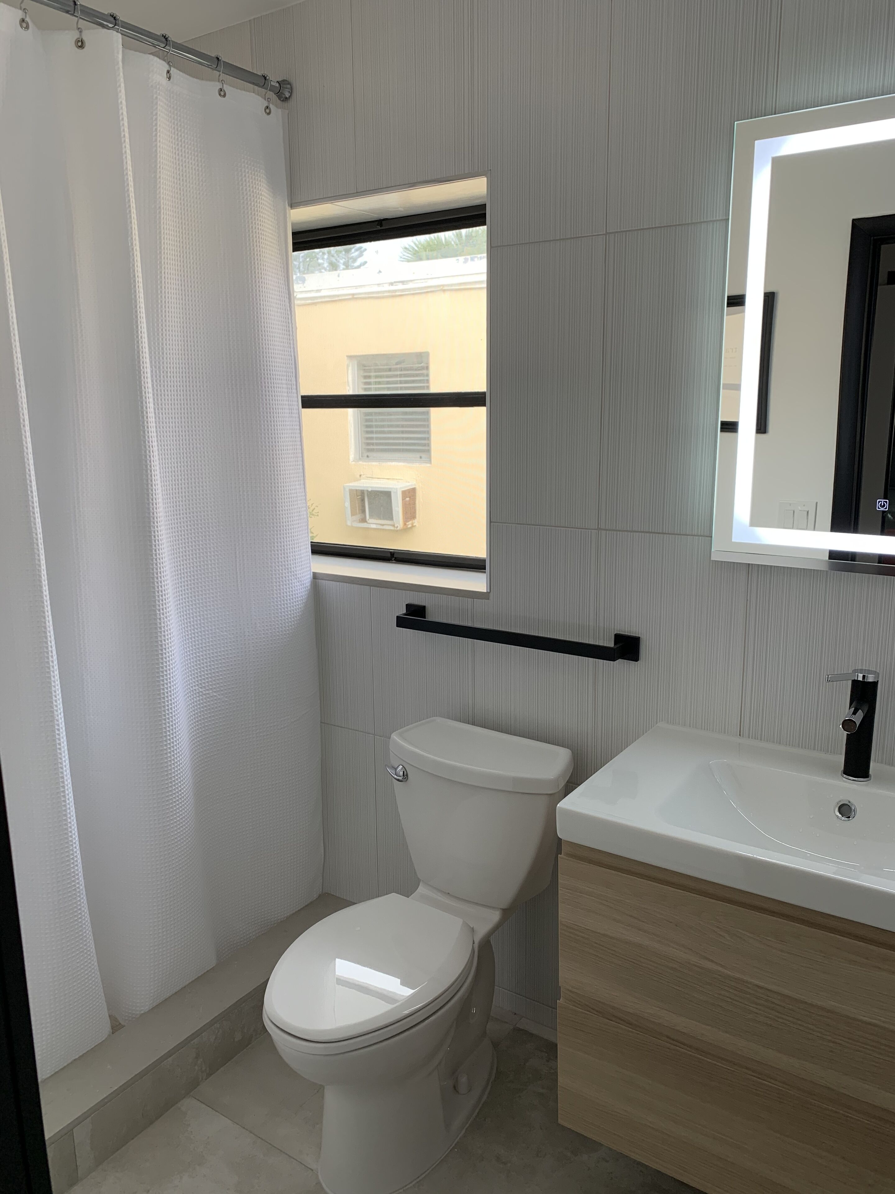A modern bathroom with a toilet, sink, and shower curtain.