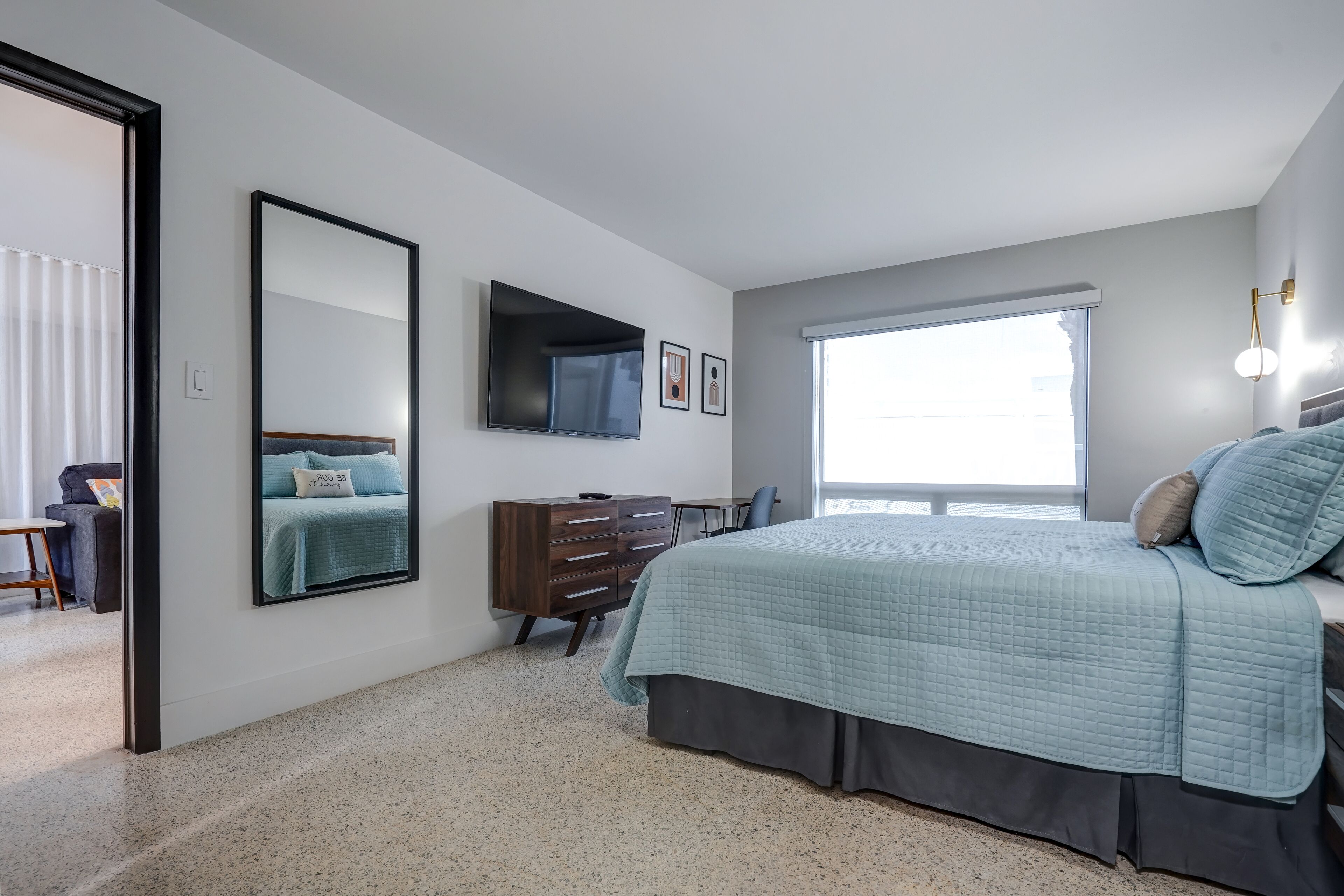A bedroom with a bed, dresser, TV, and a window.