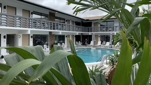 Un hotel con piscina, asientos exteriores y un patio cubierto.
