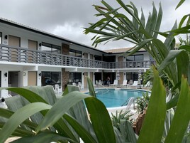 Un hotel con piscina, asientos exteriores y un patio cubierto.