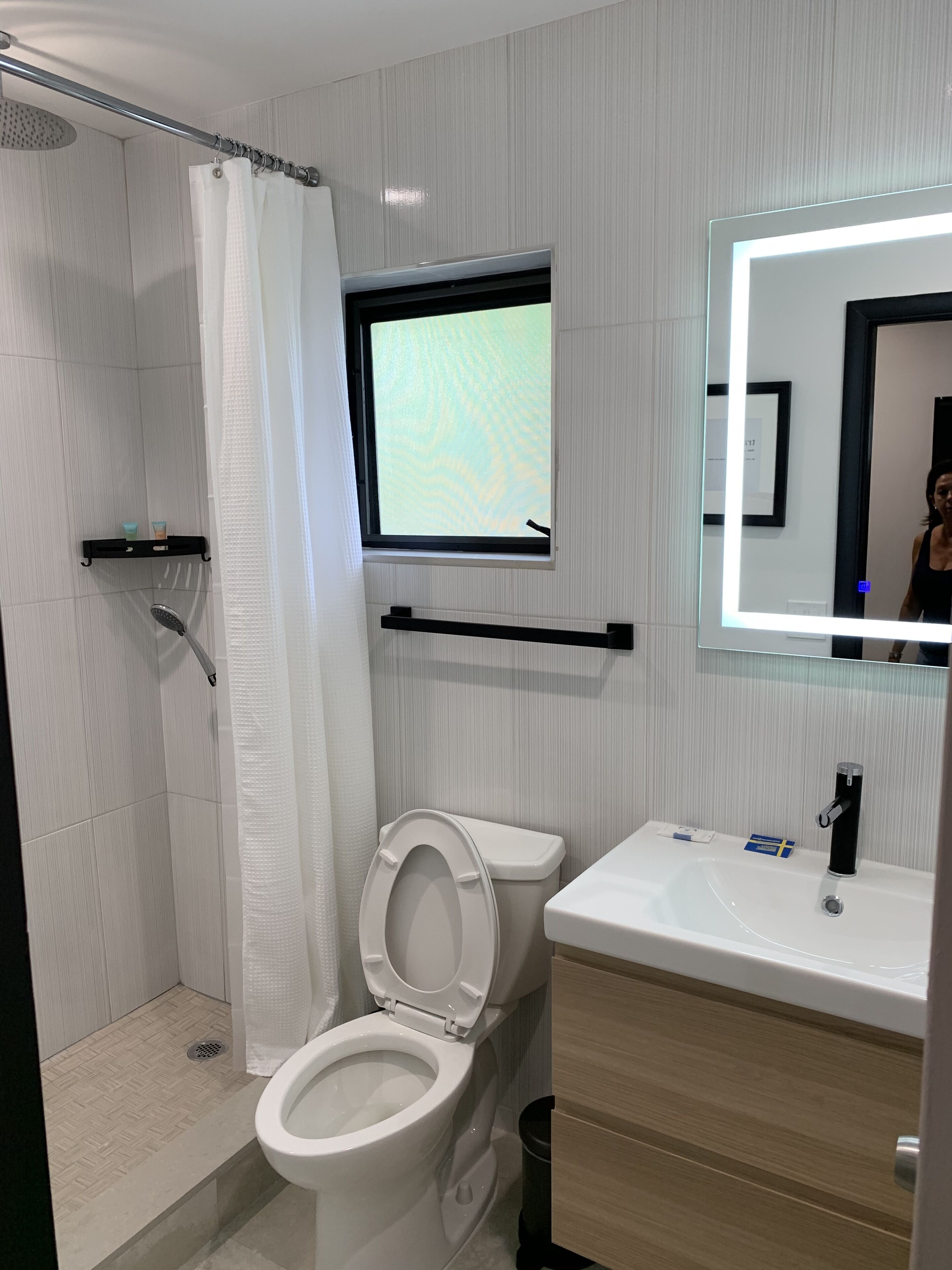 Une salle de bain moderne équipée d’une douche, de toilettes, d’un lavabo et d’une fenêtre donnant sur un beau paysage.