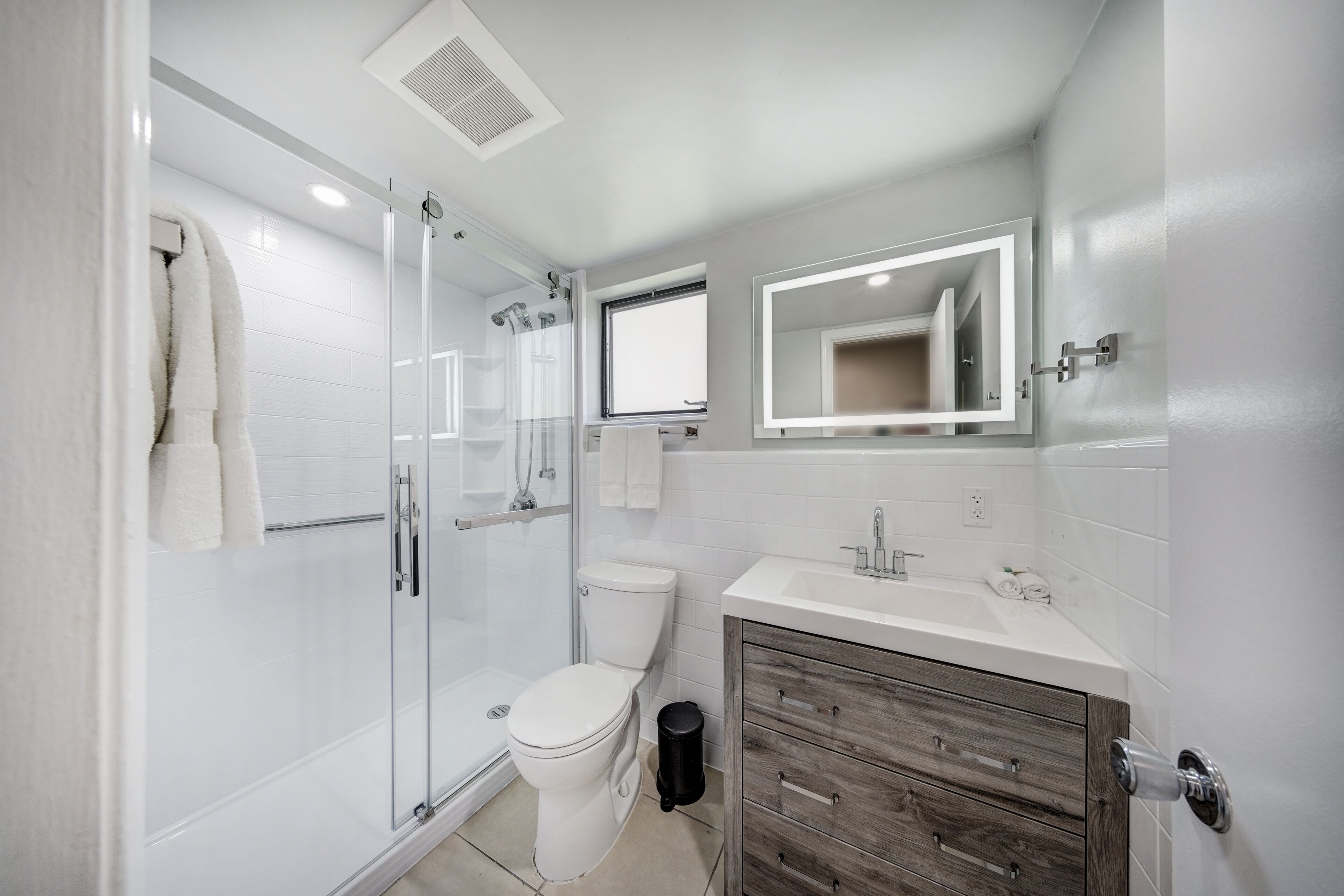 Une salle de bain moderne avec une douche à parois de verre, des toilettes, un lavabo avec un miroir et des meubles en bois.