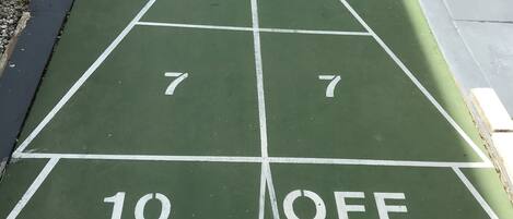 A green shuffleboard court with numbers 7, 8, 10, and OFF marked on it.