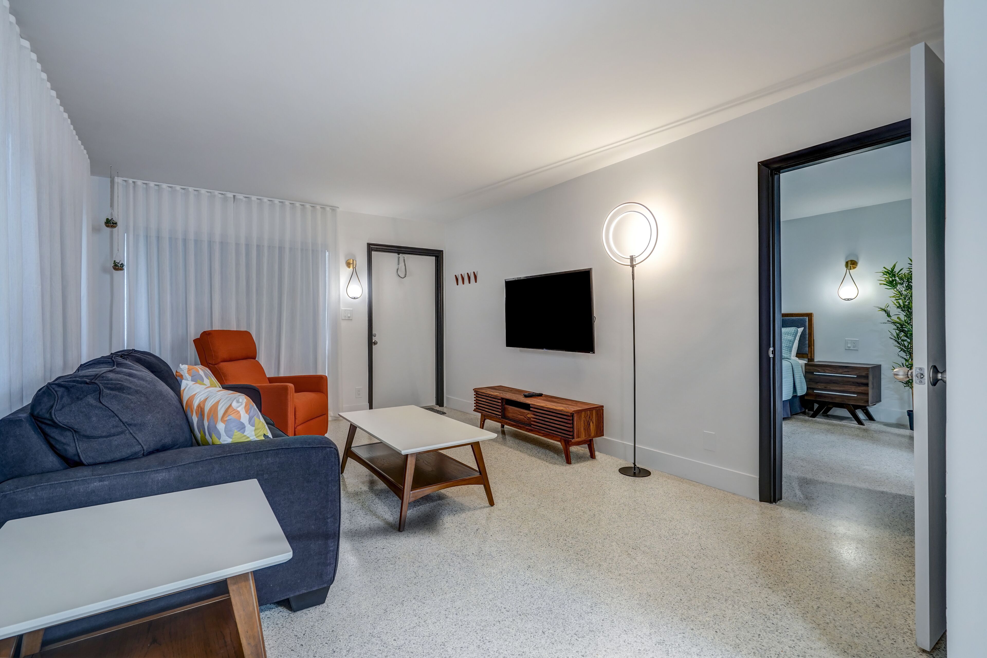 Een moderne woonkamer met een bank, salontafel en televisie. Er is een houten kast en een vloerlamp.