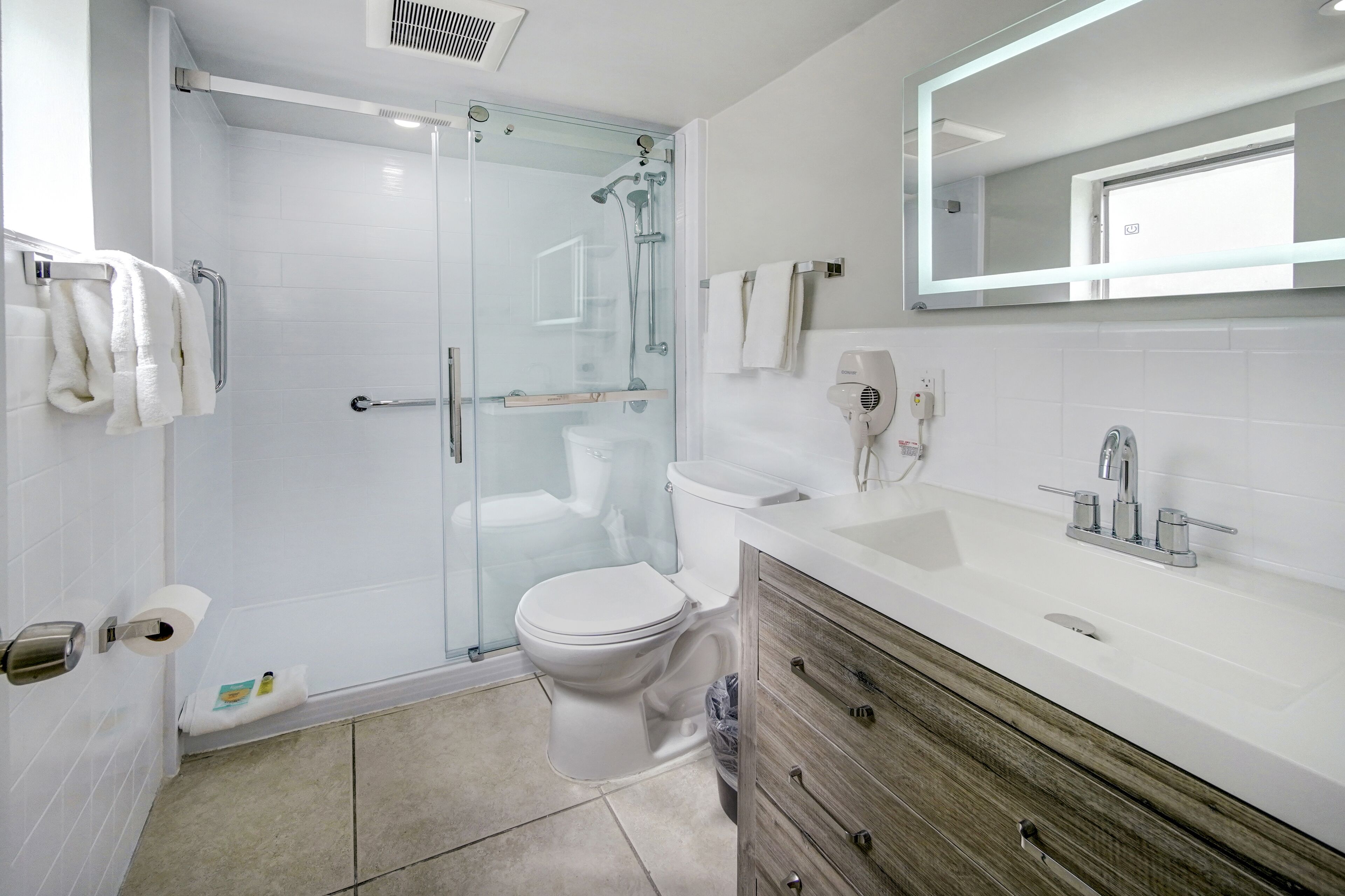 Une salle de bain moderne avec une douche à parois de verre, des toilettes blanches et un meuble-lavabo en bois avec un évier.