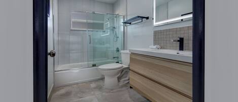 Un bagno moderno con doccia vetrata, un water bianco e un mobile lavabo in legno con specchio.