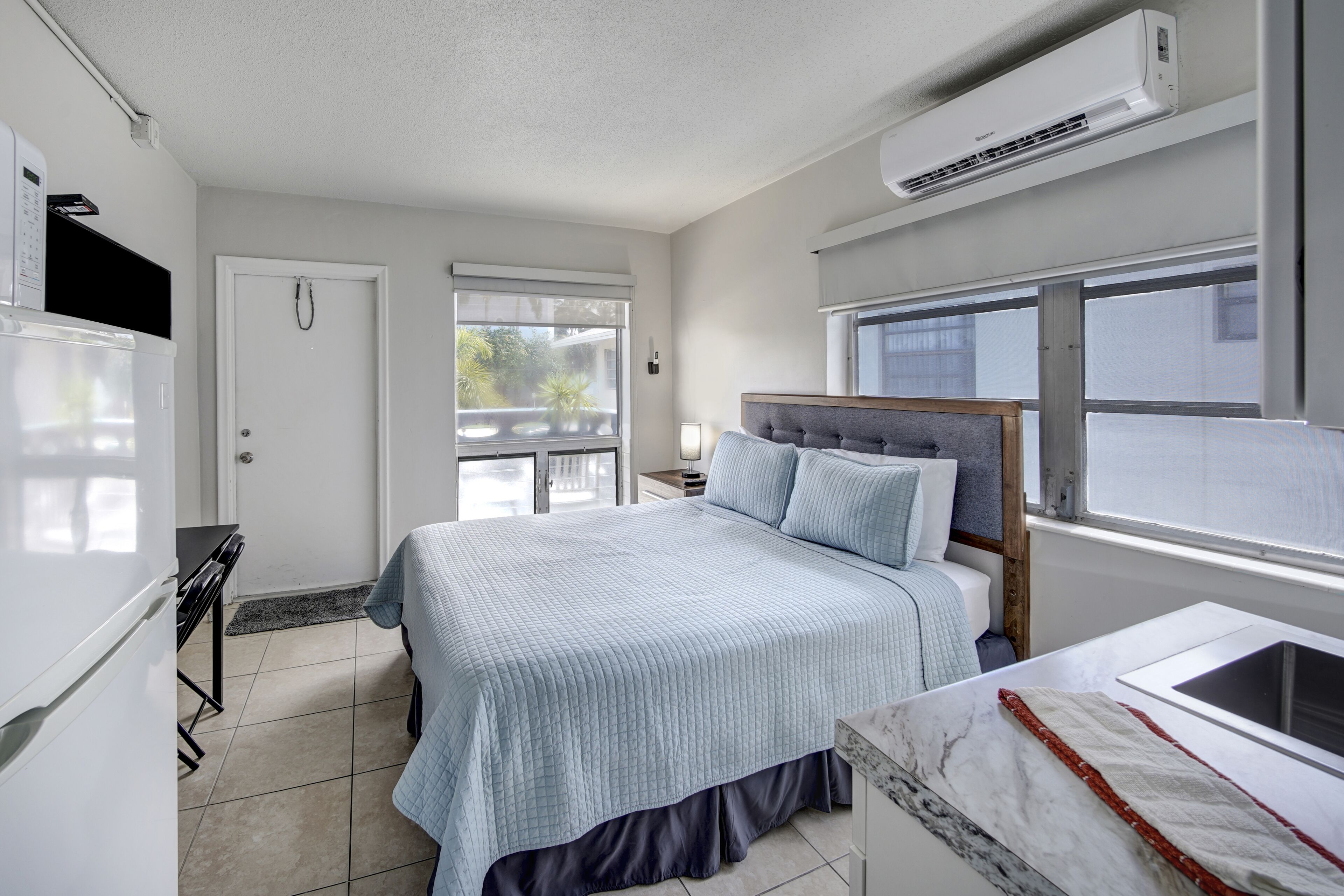 A modern bedroom with a bed, bedside table, and a window.