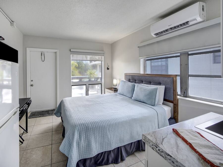 A modern bedroom with a bed, bedside table, and a window.