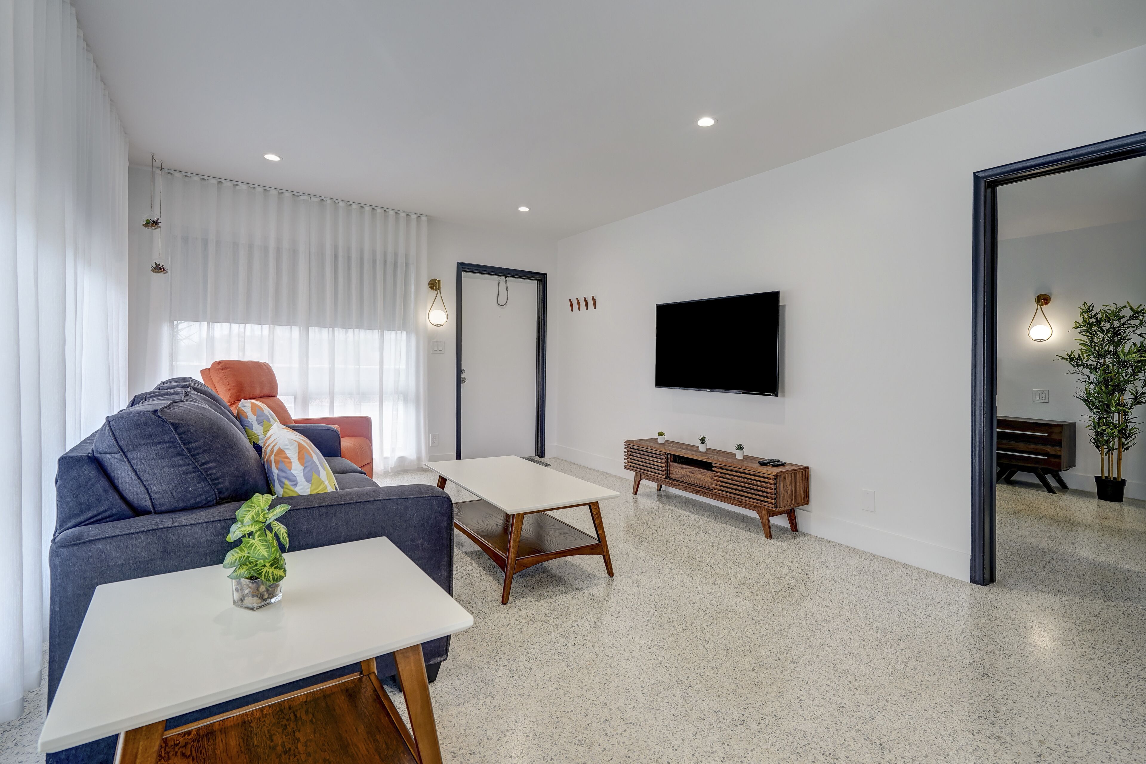 A modern living room with a sofa, a coffee table, a TV, and a small cabinet.