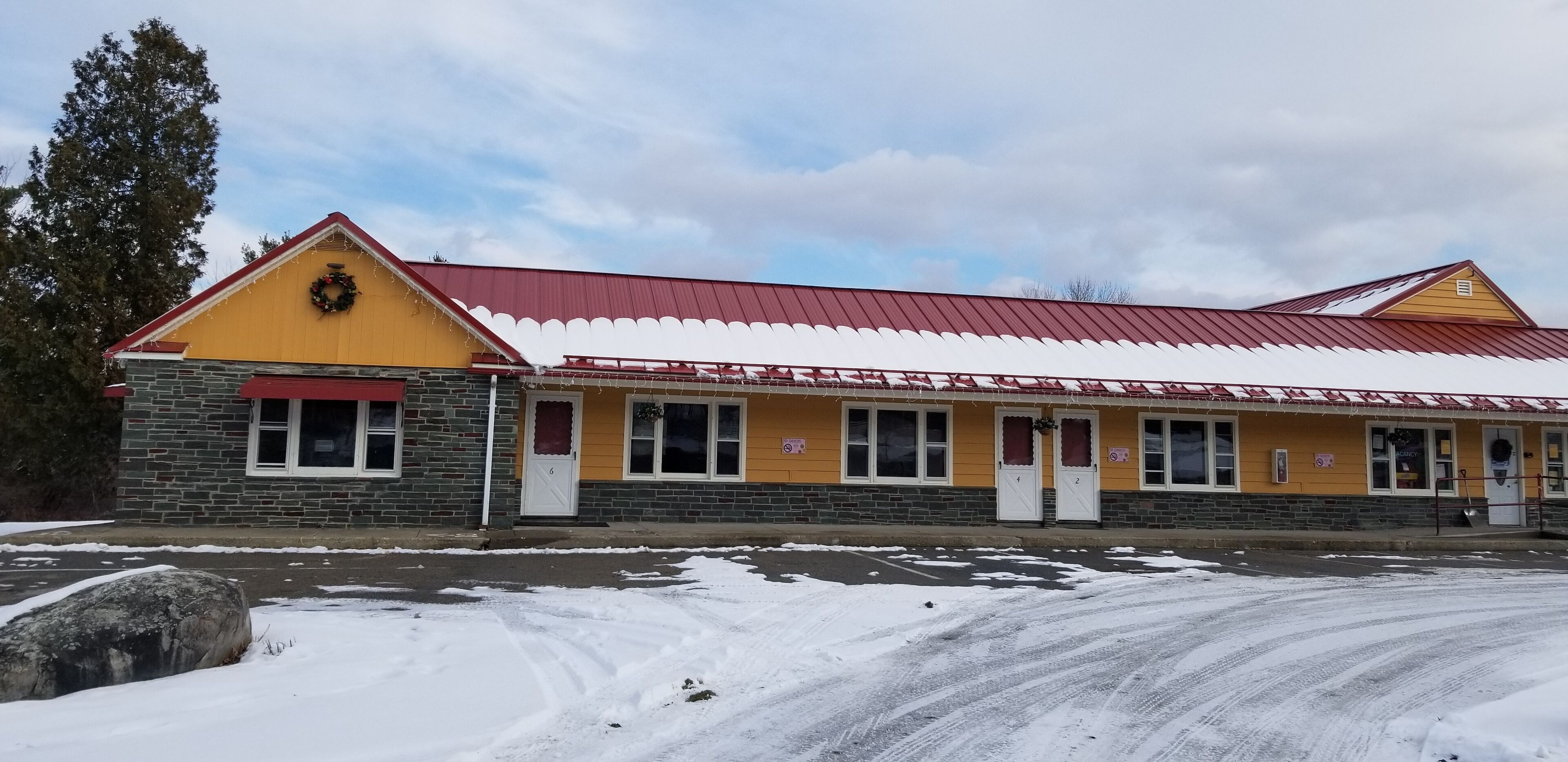 A two-story building with a red roof and yellow walls, featuring multiple windows and doors.