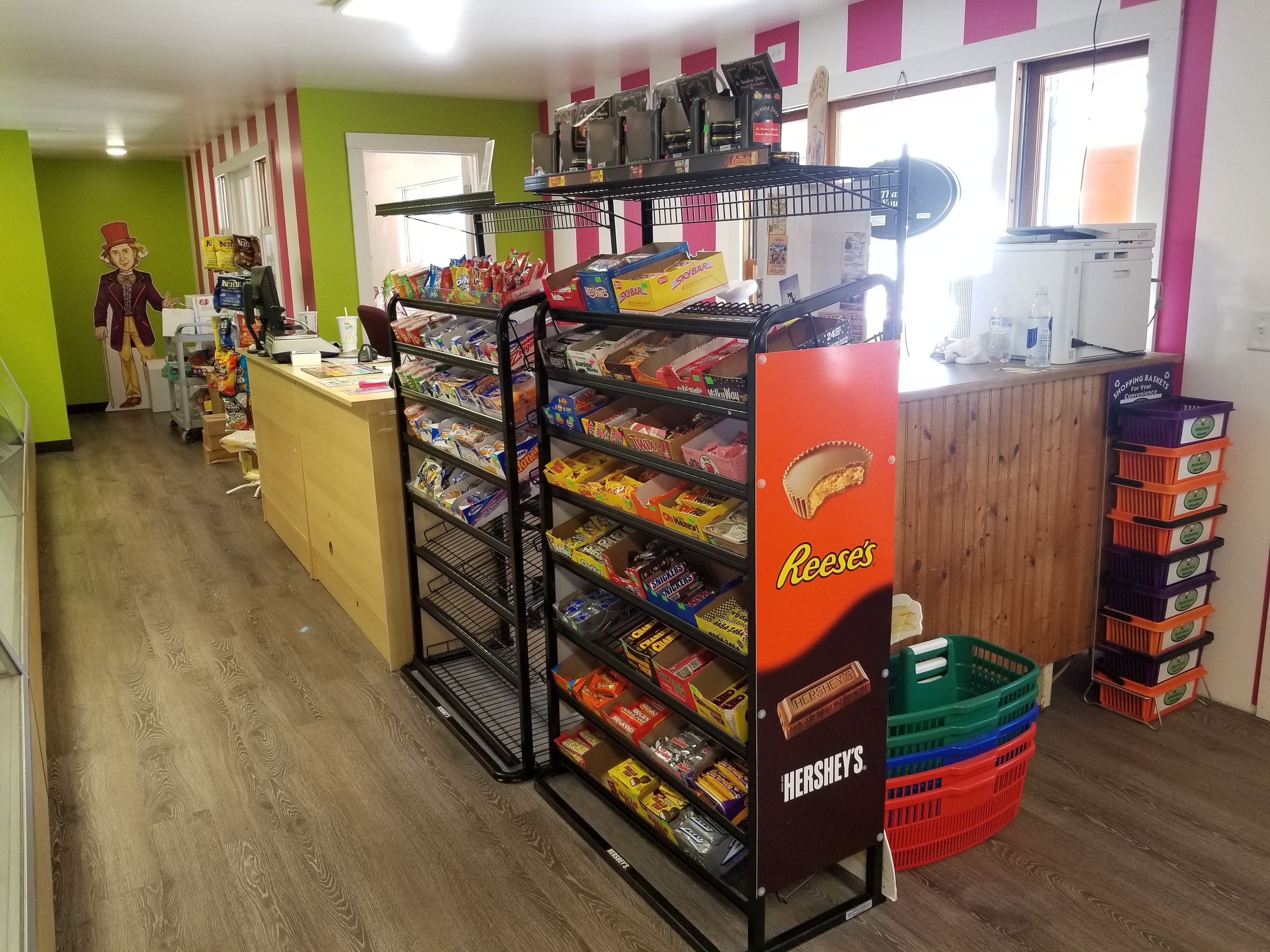 A candy store with shelves stocked with various candies and a display for Hershey's and Reese's.
