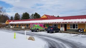 A building with a red roof and yellow walls, featuring a colorful van parked in front.