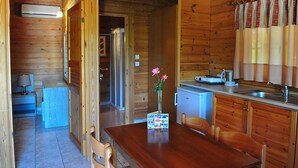 A wooden cabin with a dining area, kitchen, and a bathroom. - Sandy's Studios Apartments & Log Villas (Kos)