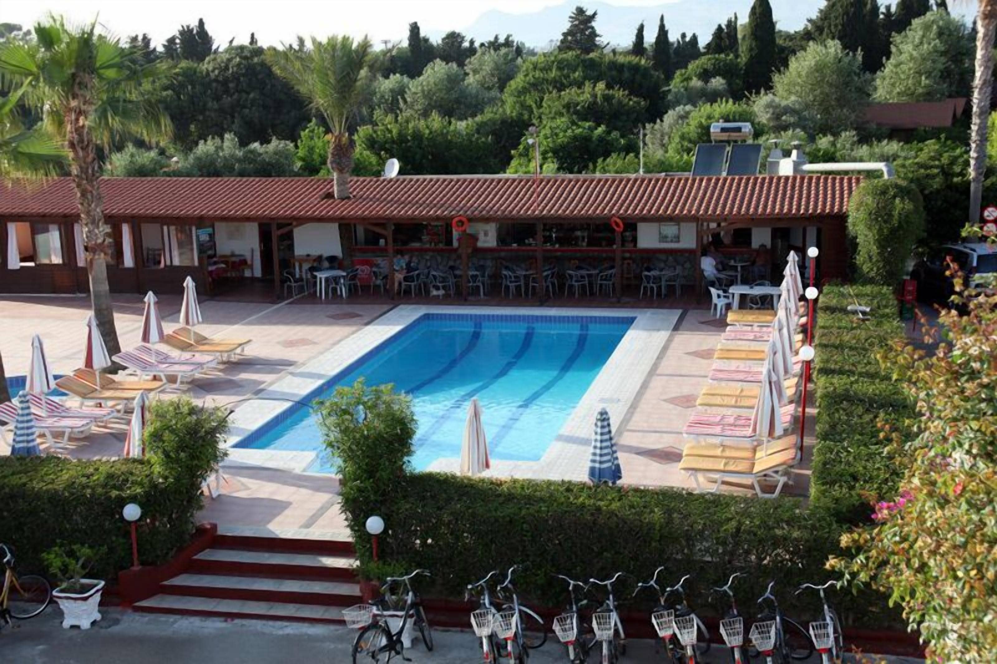 Un espace piscine aménagé avec des chaises longues, des parasols et un coin bar doté de tables et de chaises.