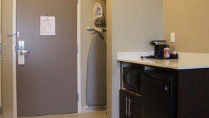Een kleine keuken met een koelkast, magnetron en koffiezetapparaat.