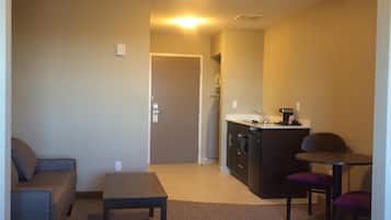 Un espacio habitable compacto con kitchenette, un sofá, una pequeña mesa y una silla.