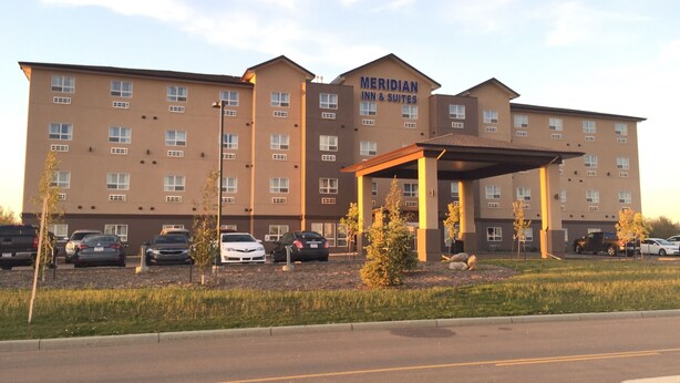 Un hotel de varios pisos con un letrero llamativo que dice "MERIDIAN INN & SUITES".