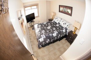 Relax in a stylish room with a large bed, flat-screen TV, and a bedside table with a lamp.