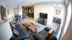 A modern living room with a sofa set, a coffee table, and a TV. - Corporate Suites of Calgary - Eightwelve (Calgary)