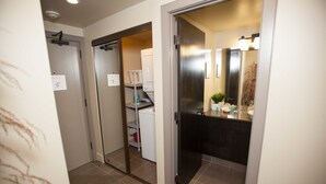 A modern bathroom with a shower, a toilet, and a sink. There is a mirror above the sink and a plant on the counter. - Corporate Suites of Calgary - Eightwelve (Calgary)
