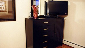 Un meuble de rangement noir pour appareils électroniques, doté d’un téléviseur à écran plat et d’un vase décoratif.