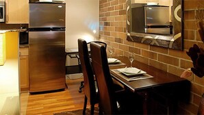 Une cuisine moderne dotée d’appareils électroménagers en acier inoxydable, d’une table à manger avec des chaises, et d’un mur de briques en guise de pare-feu.