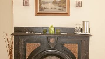 A fireplace with a mantel, a framed painting above it, and a vase on the mantel.
