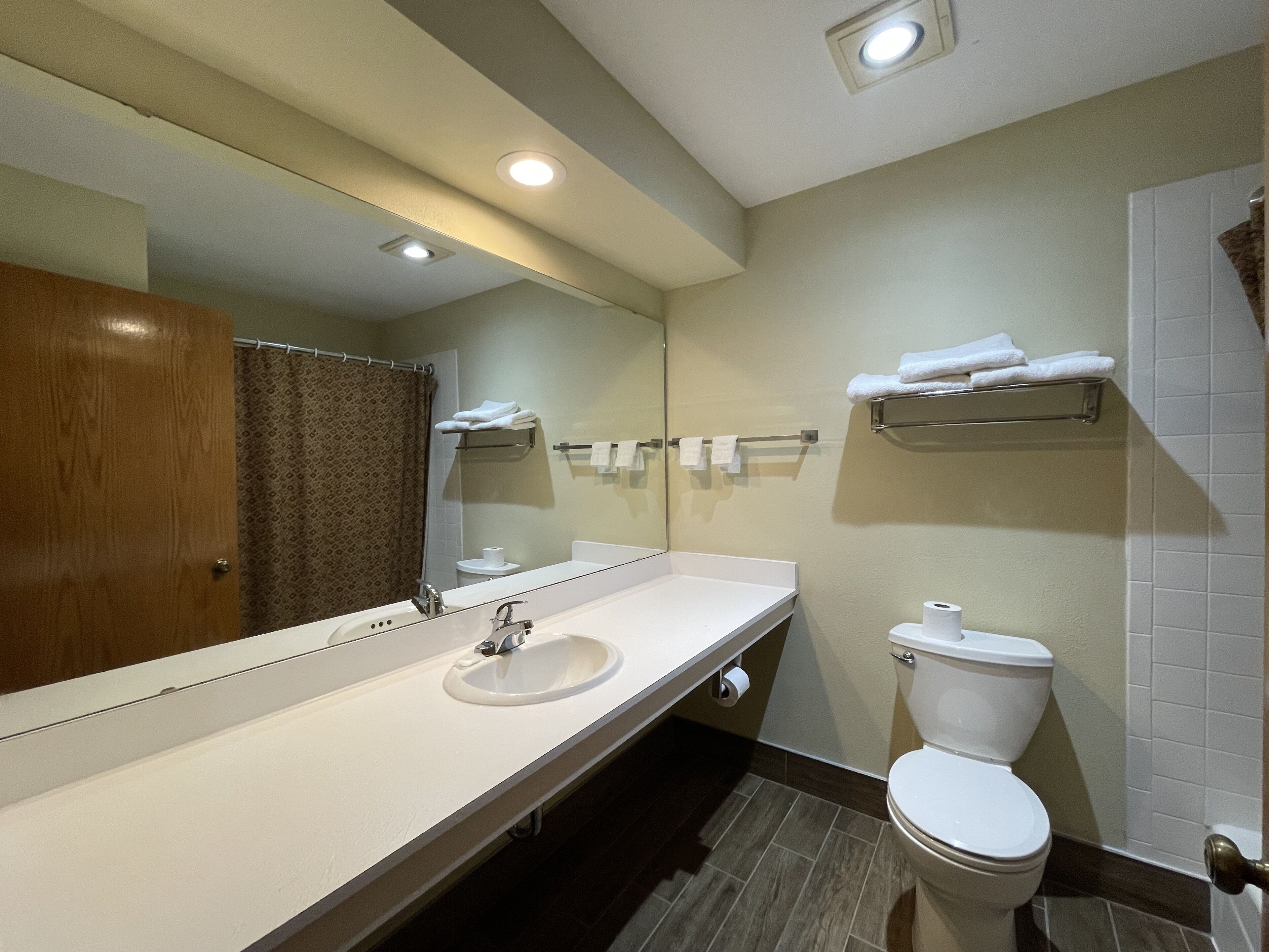 A modern bathroom with a sink, mirror, toilet, and towel rack.