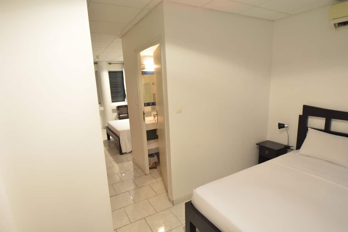 Ein Hotelzimmer mit Bett, Nachttisch, kleinem Tisch und einem durchgegangene Tür erkennbaren Badezimmer.