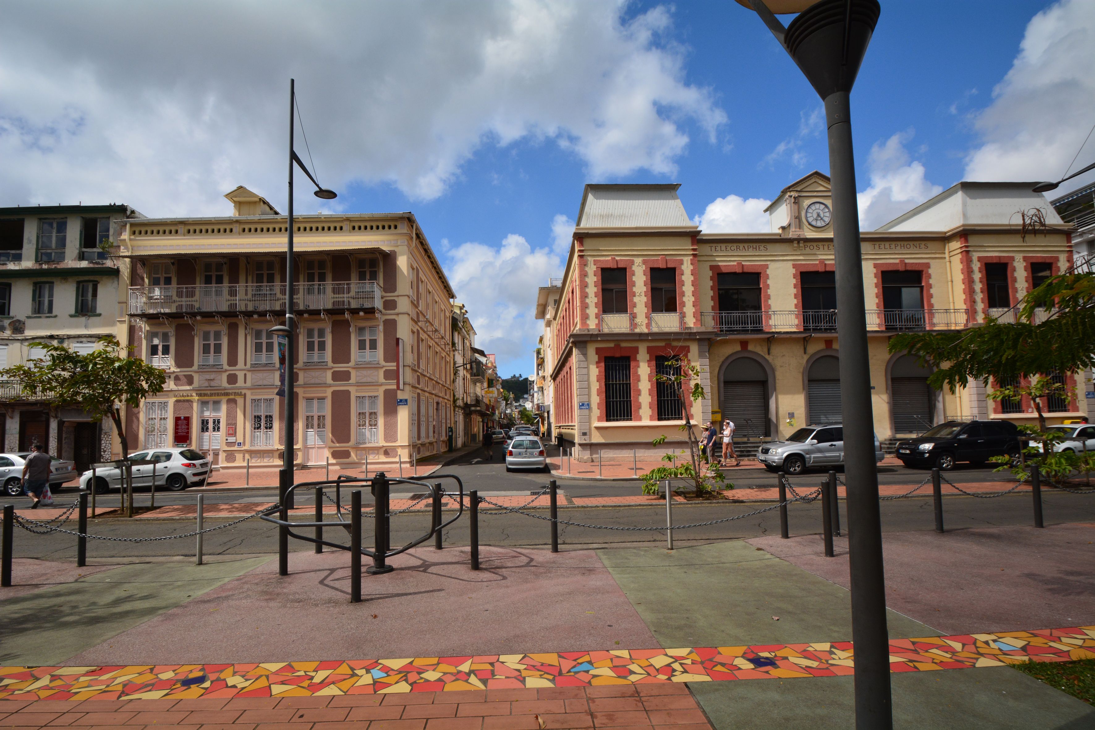 A street with buildings, a pedestrian area, and a clock tower.