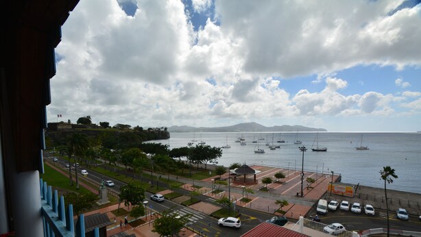 A coastal cityscape with a view of the sea, boats, and a road with cars. - Bayfront Hotel (Fort-de-France)