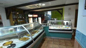 A bakery display case with pastries and a refrigerated section with beverages. - Bayfront Hotel (Fort-de-France)