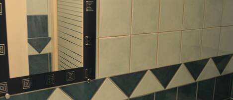 Une salle de bain avec un lavabo, un miroir, des toilettes et des carreaux décorés.