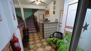 A lobby with a staircase, a reception desk, a fire extinguisher, and a potted plant. - Bayfront Hotel (Fort-de-France)
