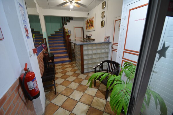 A lobby with a staircase, a reception desk, a fire extinguisher, and a potted plant. - Bayfront Hotel (Fort-de-France)