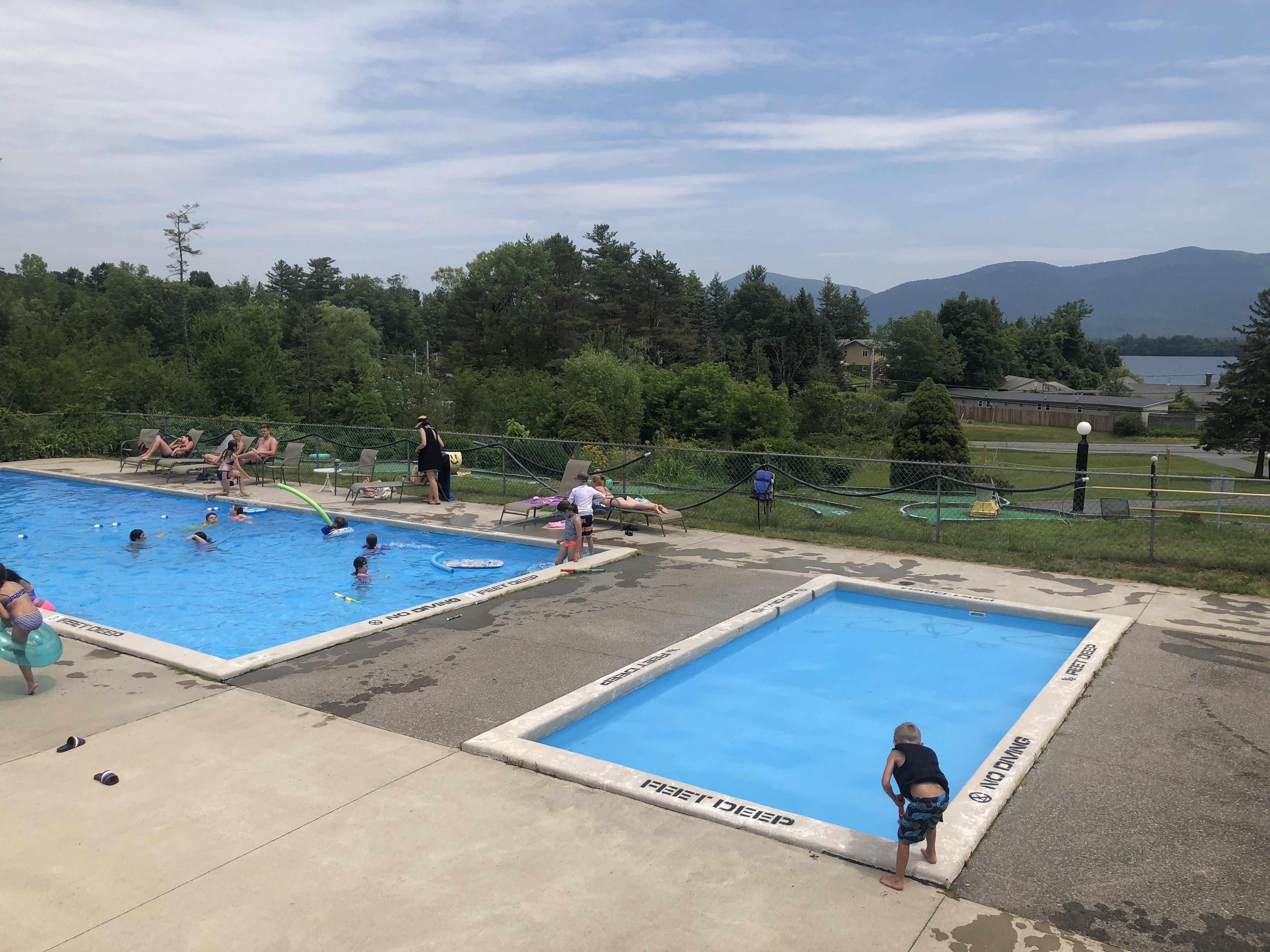 Zona de piscina con dos piscinas, un deck cercado y vistas a montañas.