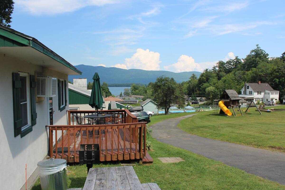 A lakeside property with a deck, picnic table, and playground.
