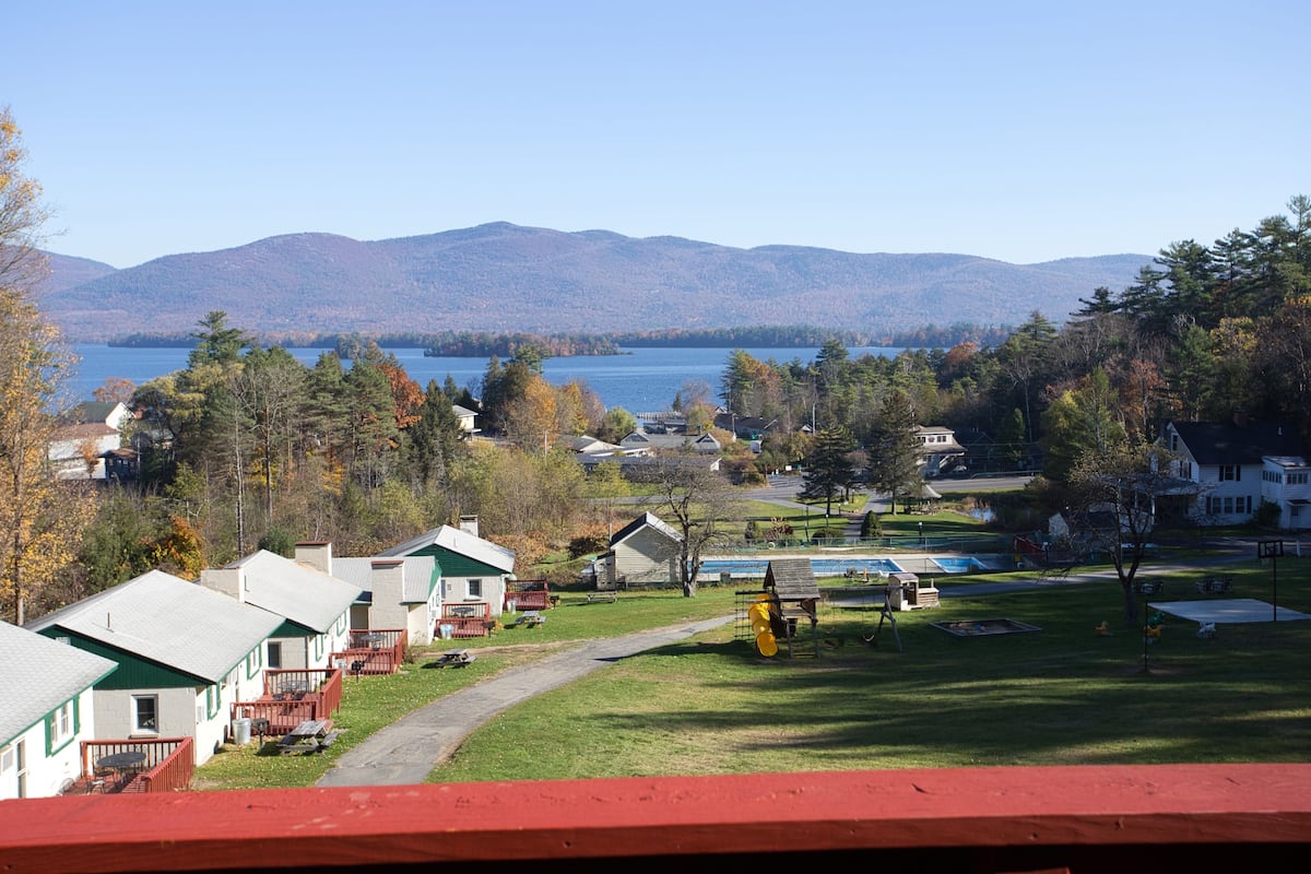 A lakeside view with cabins, a playground, and a clear sky.