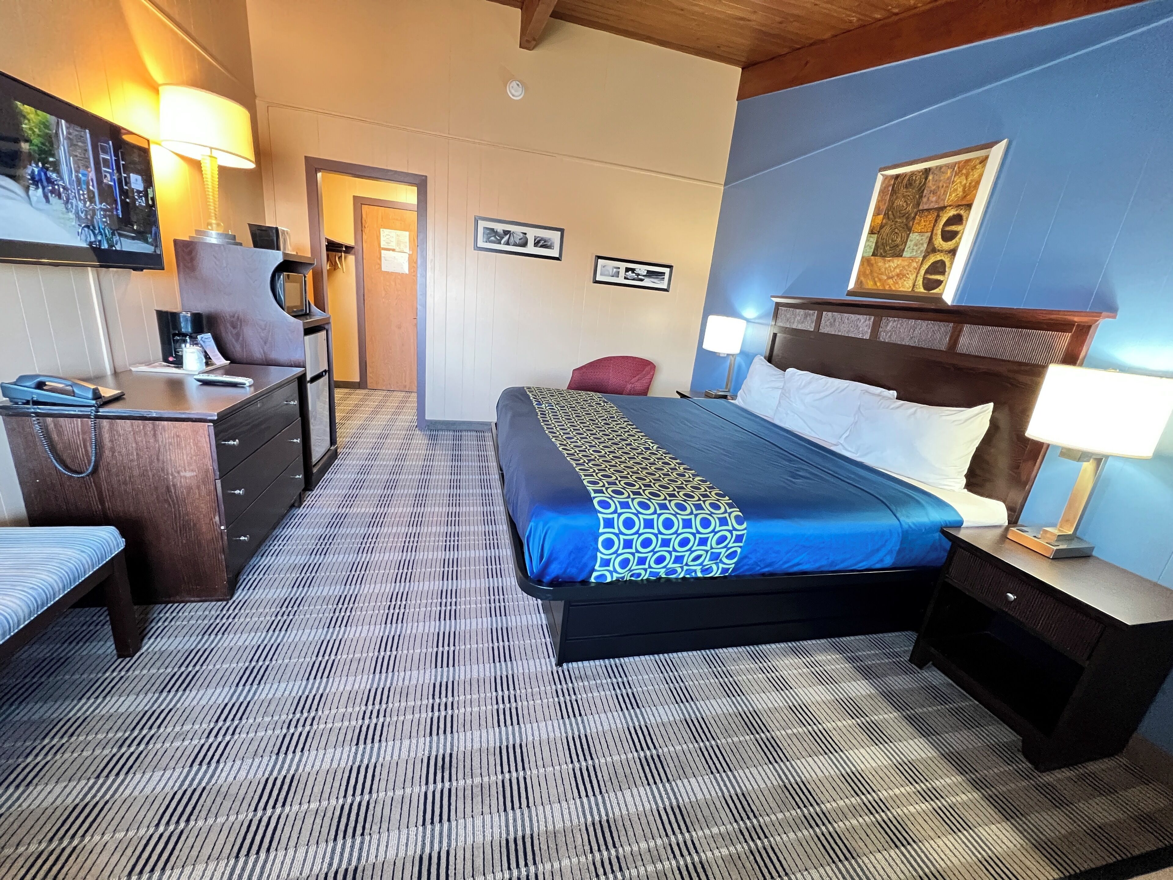 A hotel room with a bed, bedside tables, a desk, a chair, and a TV.