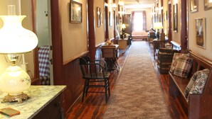 Un pasillo de hotel con pisos de madera, una zona alfombrada y un banco con cojín escocés.