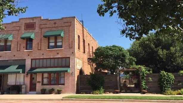 Un edificio de ladrillo de dos pisos con toldo verde y un cartel que dice 'HOTEL'.