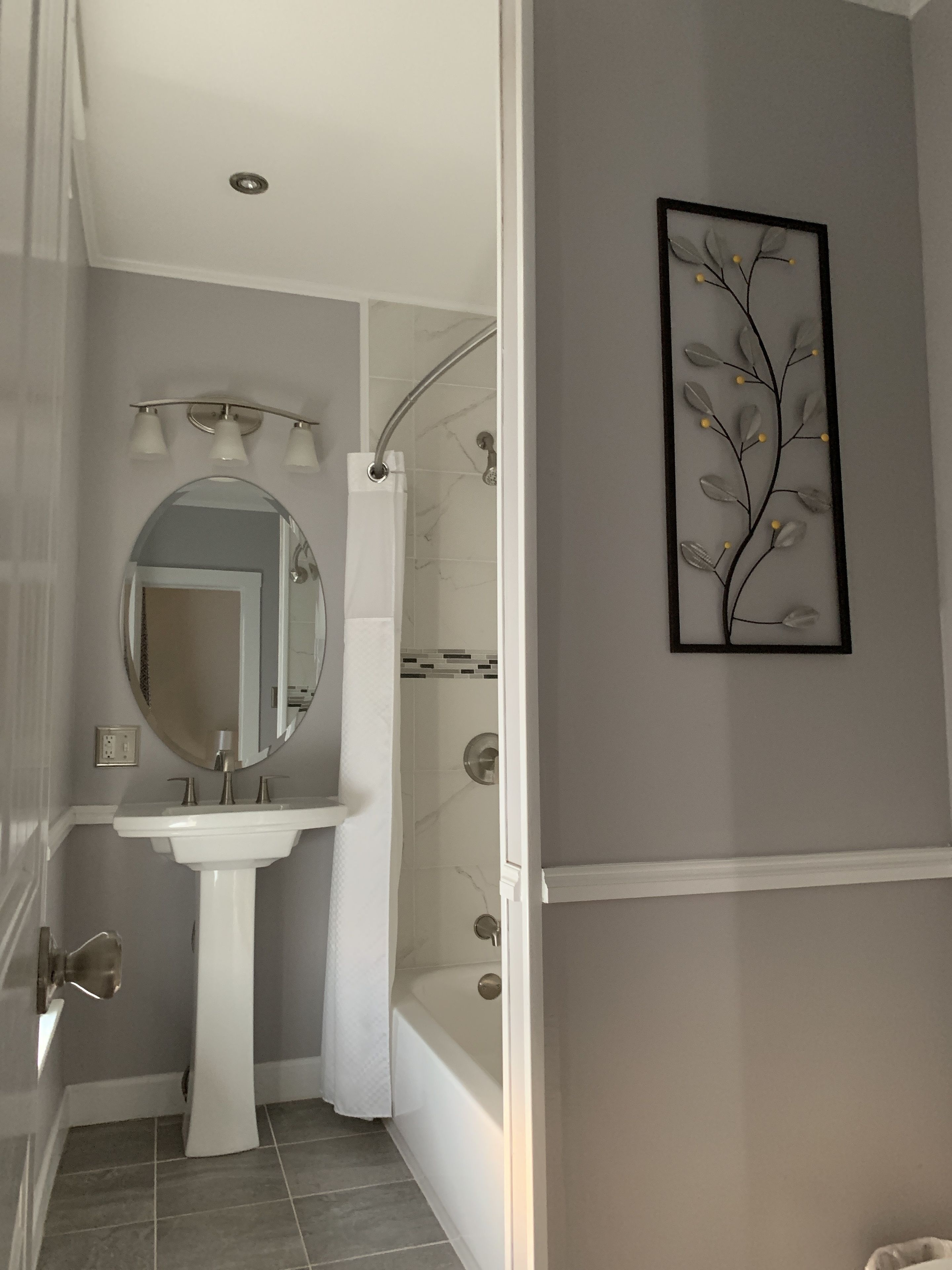Un baño con lavamanos blanco, espejo y ducha.