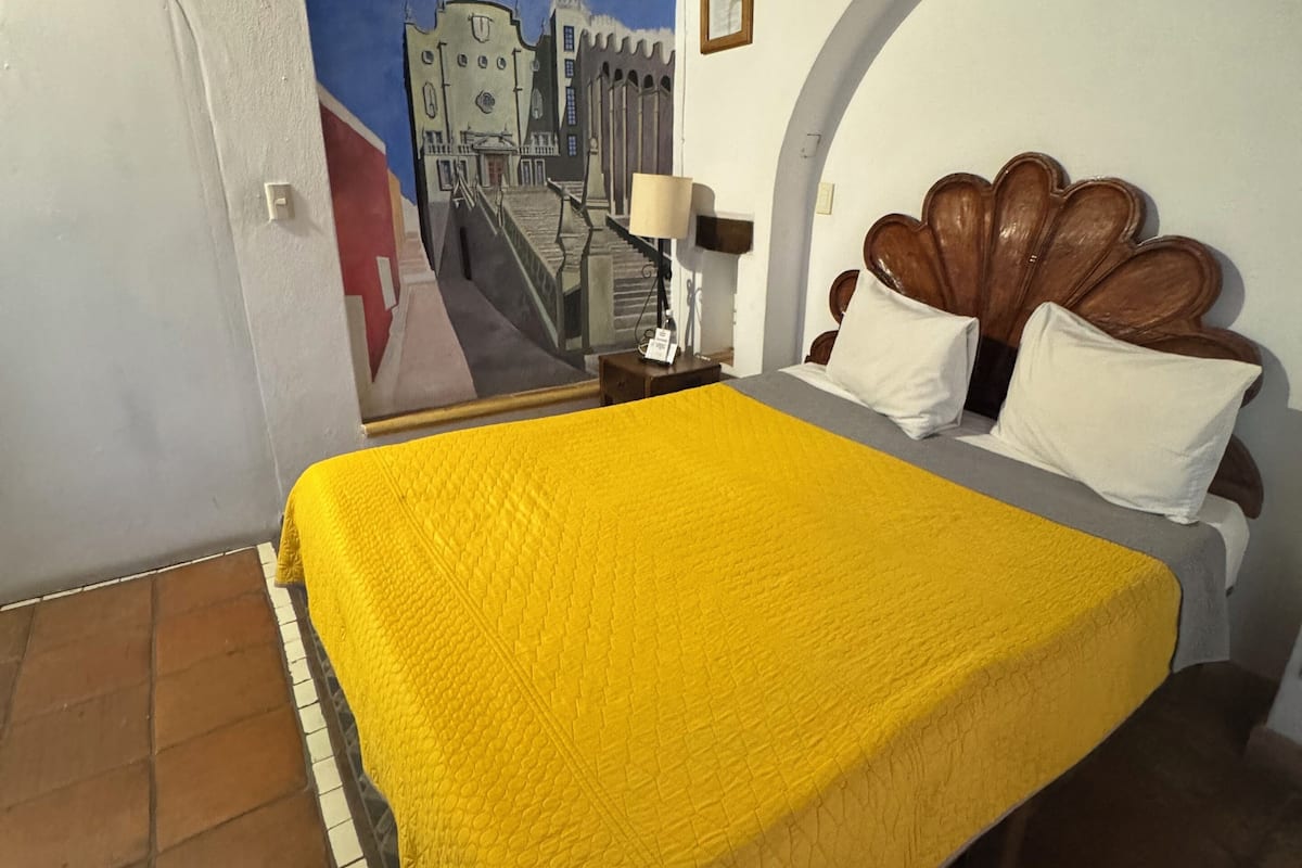 A room with a bed, a mural on the wall, and a tiled floor.