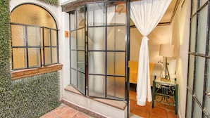 A hotel entrance with a large glass door, a small table with a lamp, and a curtain.