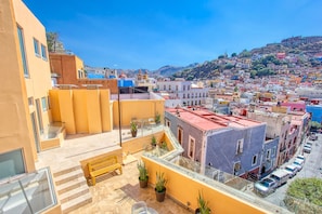 A high-rise building with multiple balconies, potted plants, and a clear view of the cityscape. - Hotel Real Guanajuato (Guanajuato)