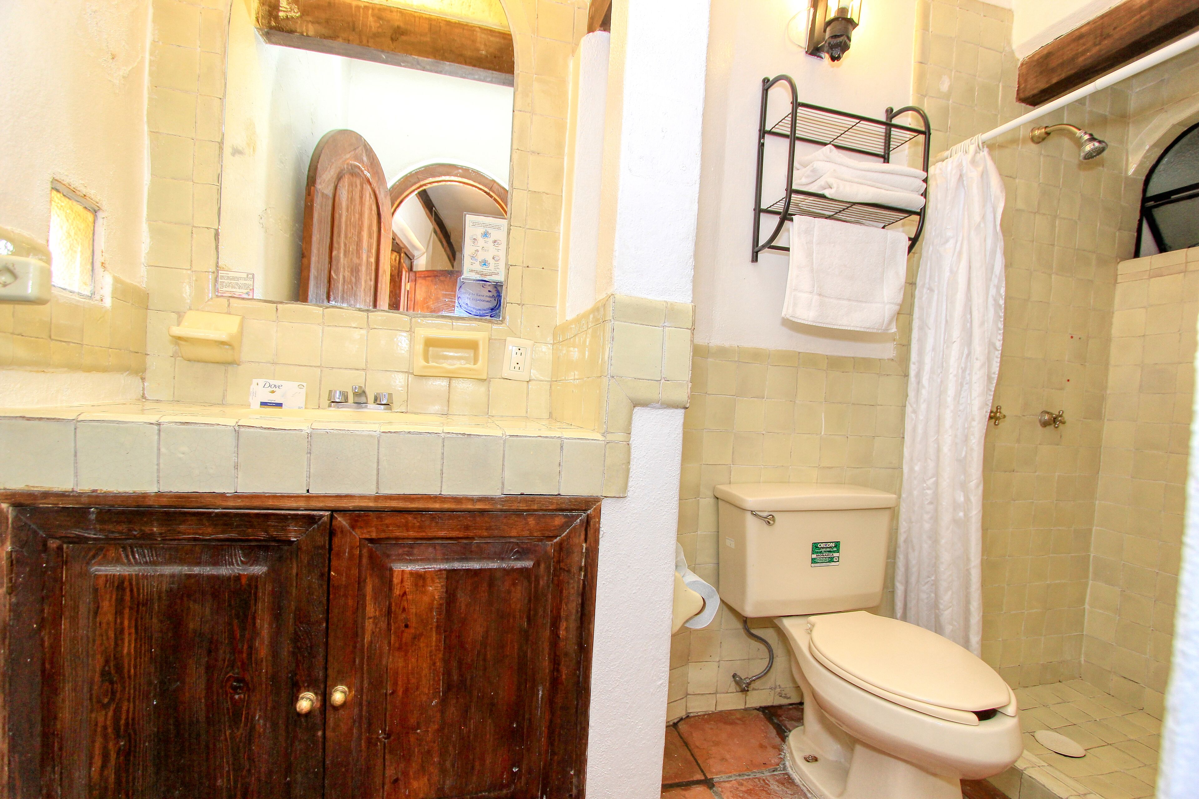 Un baño con tocador de madera, inodoro, ducha y perchero para toallas.
