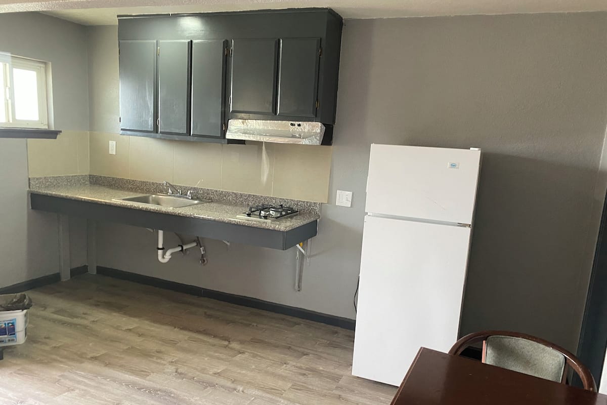 A kitchen with dark cabinets, a white refrigerator, and a granite countertop.