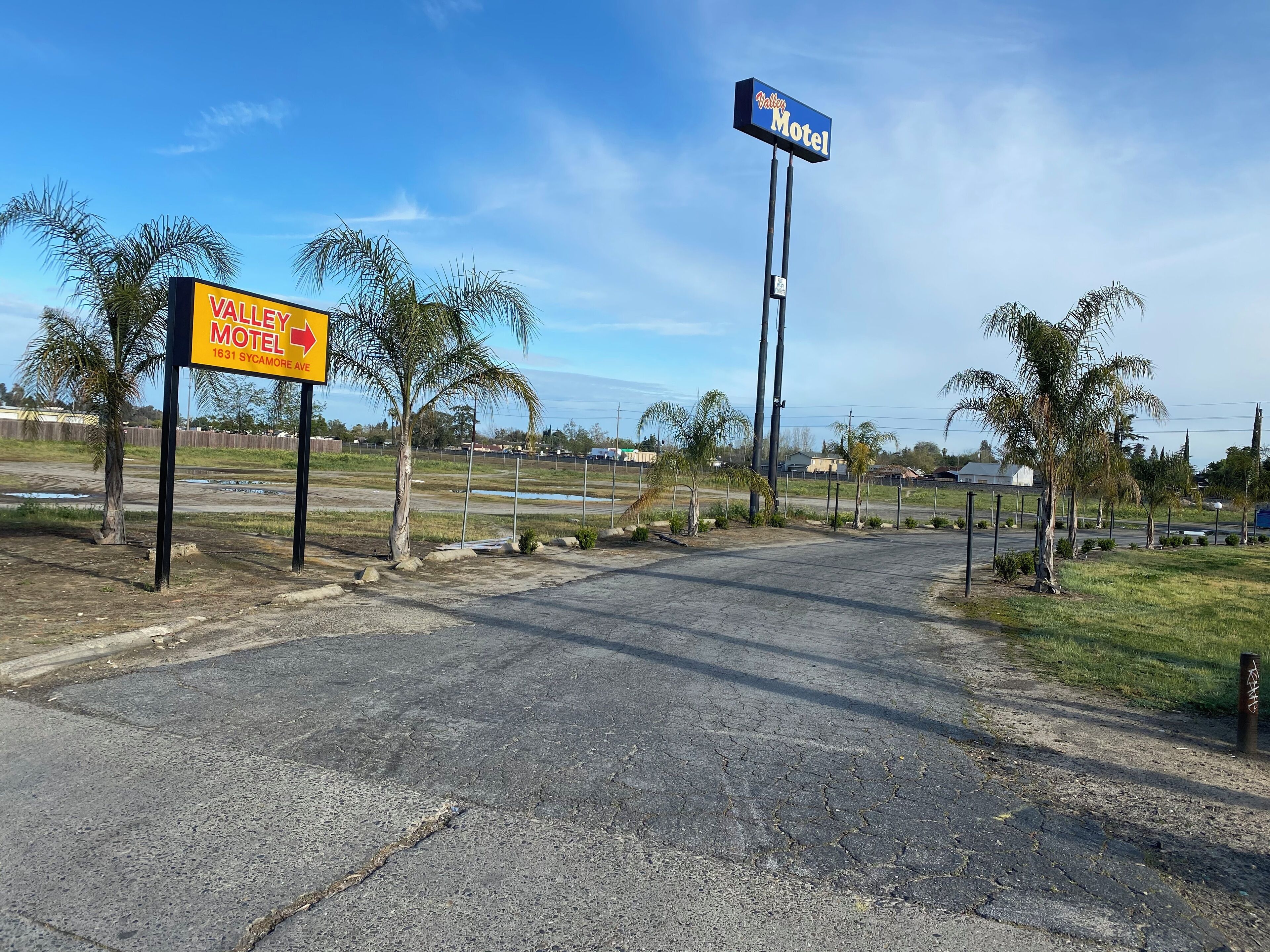 Señal de motel con flechas direccionales y vista de la calle.