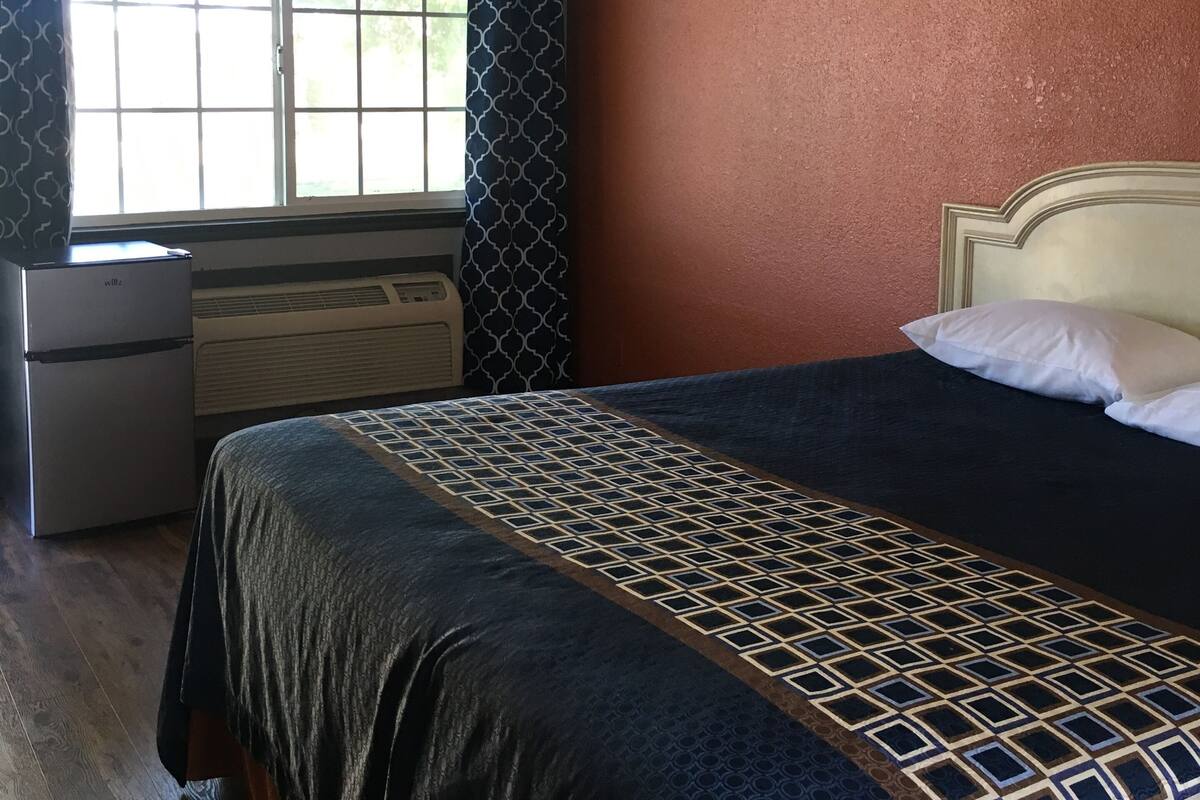 A bedroom with a bed, dresser, and window.